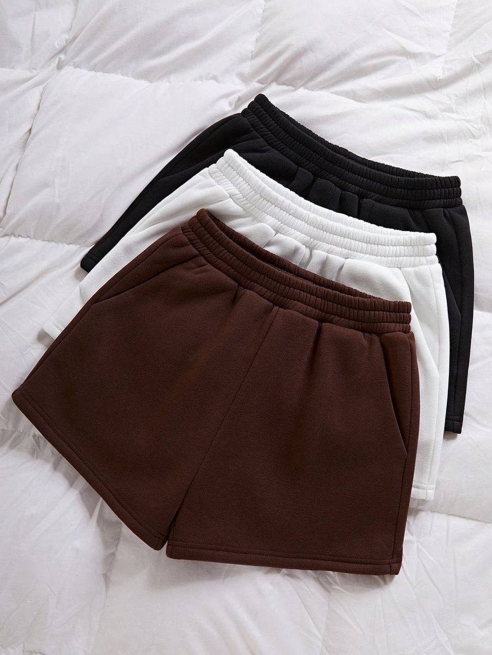 Brown, white and black fleece lounge shorts on white bedding